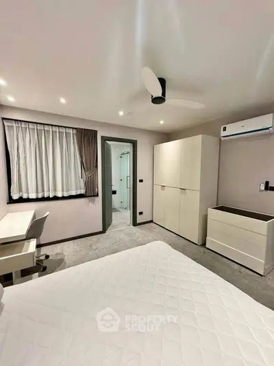 Modern bedroom with sleek furniture and ensuite bathroom in a stylish apartment.
