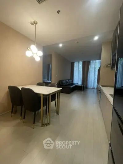 Modern open-plan living room and kitchen with elegant dining area and stylish lighting.