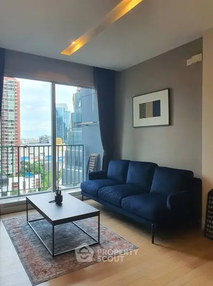 Modern living room with blue sofa and city view balcony in high-rise apartment.