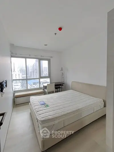 Modern bedroom with city view, featuring a large window and minimalist decor.