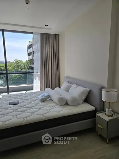 Modern bedroom with large window and balcony view, featuring a stylish bed and elegant decor.