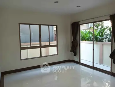 Spacious room with large windows and sliding glass door opening to a garden view, perfect for natural light.