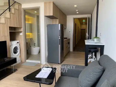 Modern apartment interior with open kitchen, living area, and visible bathroom, featuring sleek appliances.