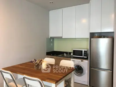 Modern kitchen with sleek appliances and wooden dining table, perfect for cozy meals.