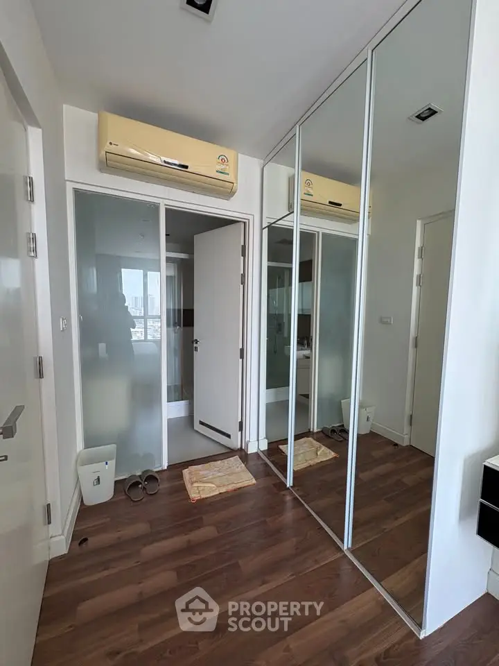 Modern apartment entryway with mirrored closet and wooden flooring