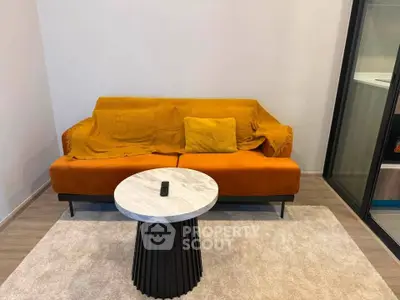 Modern living room with stylish orange sofa and chic marble coffee table on a cozy rug.