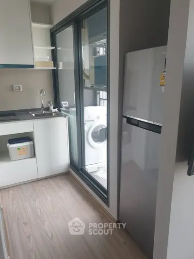 Modern kitchen with sleek appliances and wooden flooring in compact layout