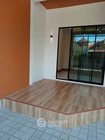 Modern home entrance with stylish wooden flooring and sliding glass doors.