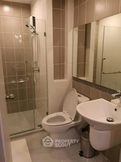 Modern bathroom with glass shower and sleek fixtures in contemporary apartment.