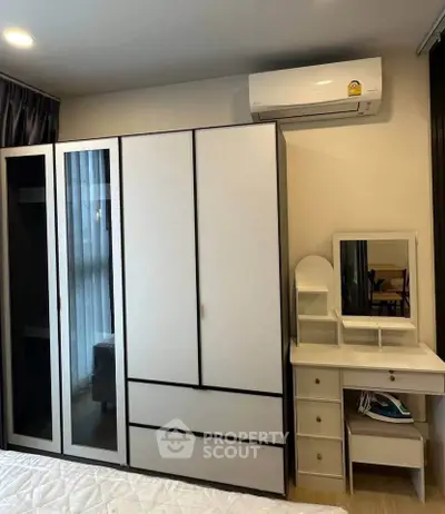 Modern bedroom with sleek wardrobe and stylish vanity set, featuring air conditioning for comfort.