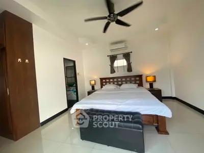 Spacious bedroom with modern furnishings and ceiling fan in a stylish apartment.