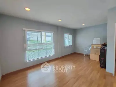 Spacious empty room with large windows and wooden flooring, perfect for customization.