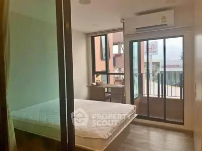 Modern bedroom with balcony access and large windows in urban apartment
