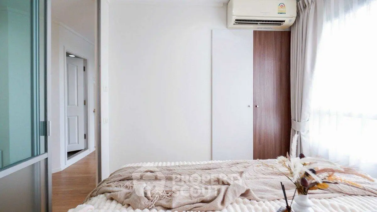 Bright bedroom with cozy decor and air conditioning, featuring soft natural light.