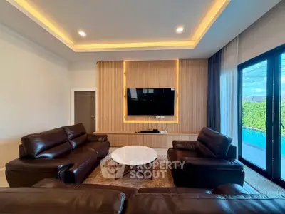 Luxurious living room with leather sofas, modern TV setup, and pool view through large windows.