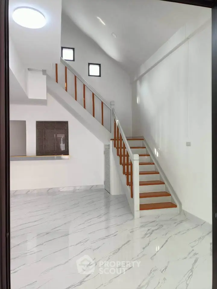Spacious modern interior with elegant staircase and marble flooring, perfect for stylish living.