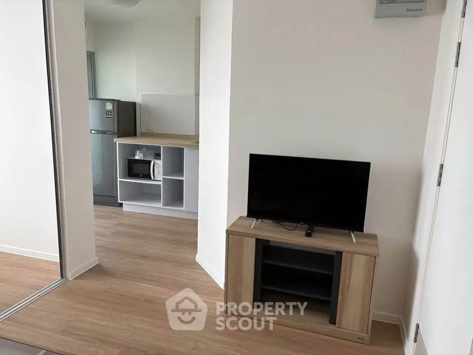 Modern apartment interior with sleek kitchen and cozy living area featuring a flat-screen TV.