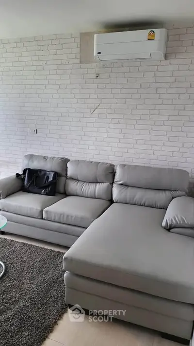 Modern living room with stylish gray sectional sofa and white brick accent wall.