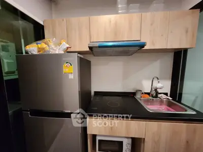Modern kitchen with sleek appliances and wooden cabinets, featuring a stainless steel fridge and electric stove.