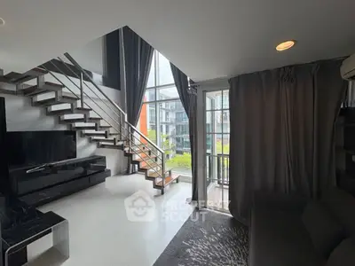 Modern duplex living room with large windows and stylish staircase