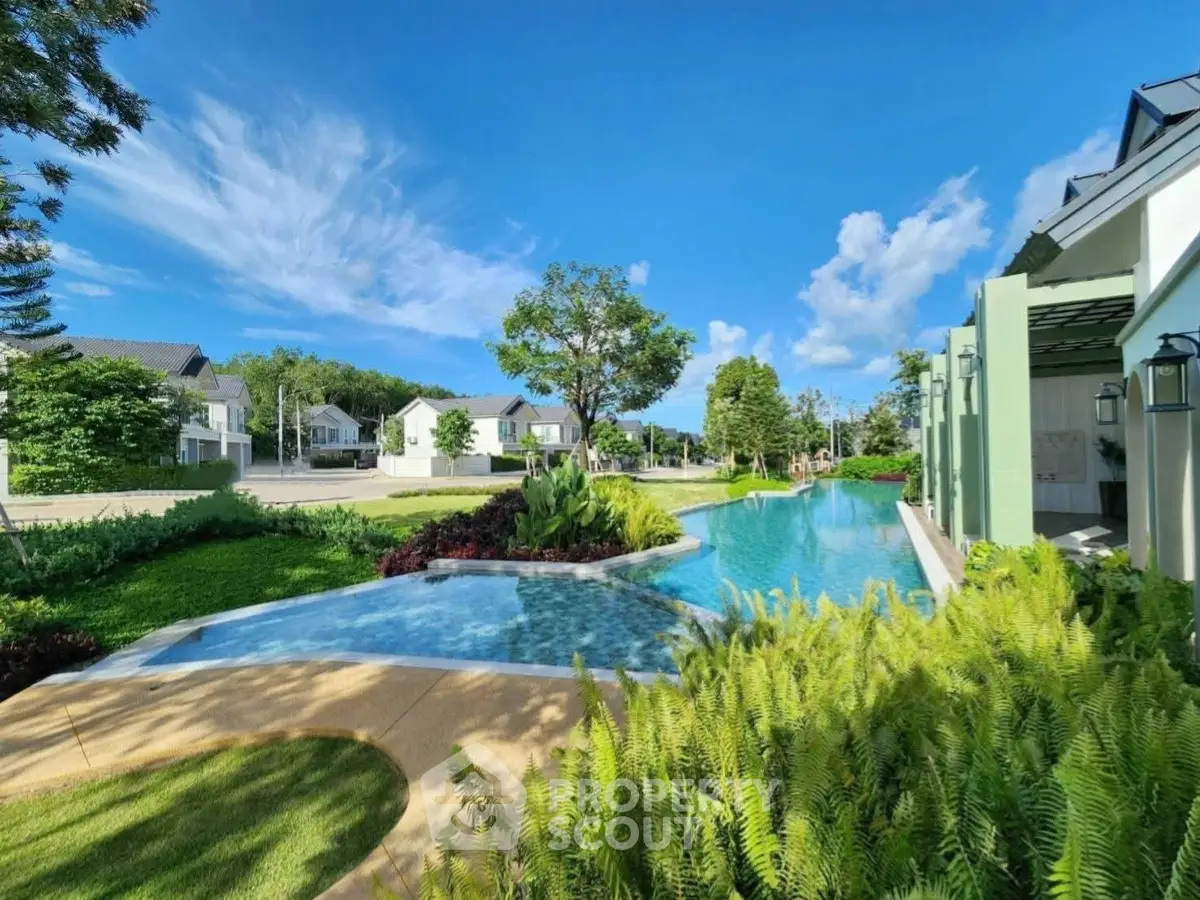 Luxurious residential community with stunning pool and lush greenery under a clear blue sky.