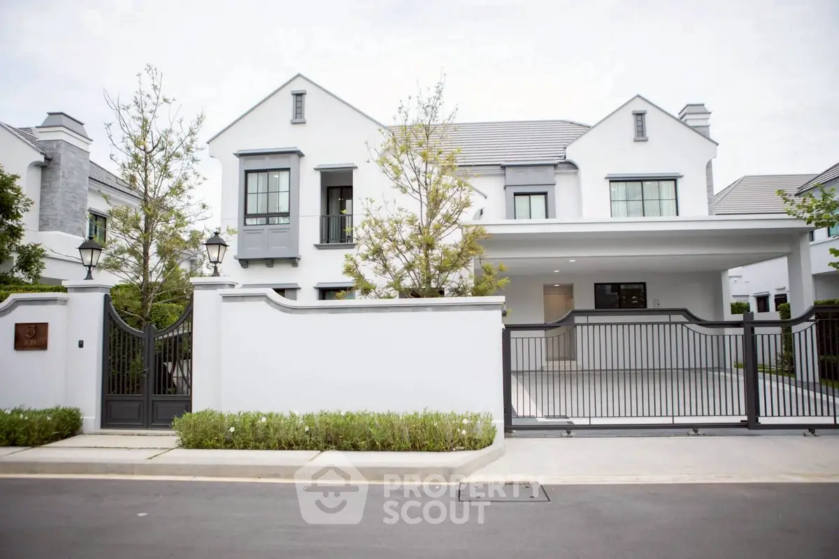 Elegant modern house with gated entrance and spacious driveway in a serene neighborhood.