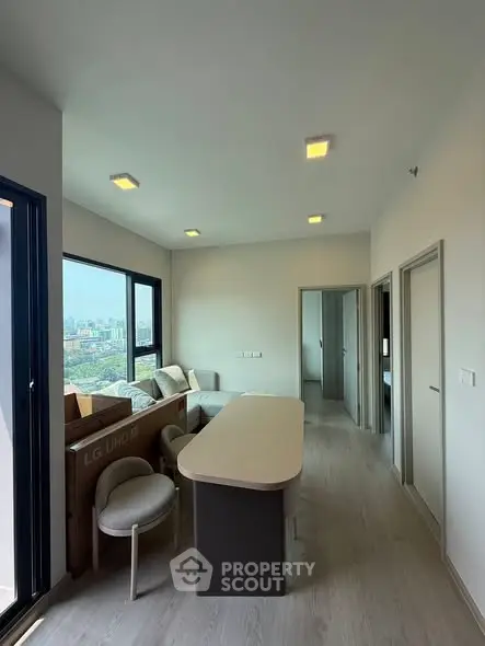 Modern living room with large windows offering stunning city views, featuring sleek furniture and contemporary design.