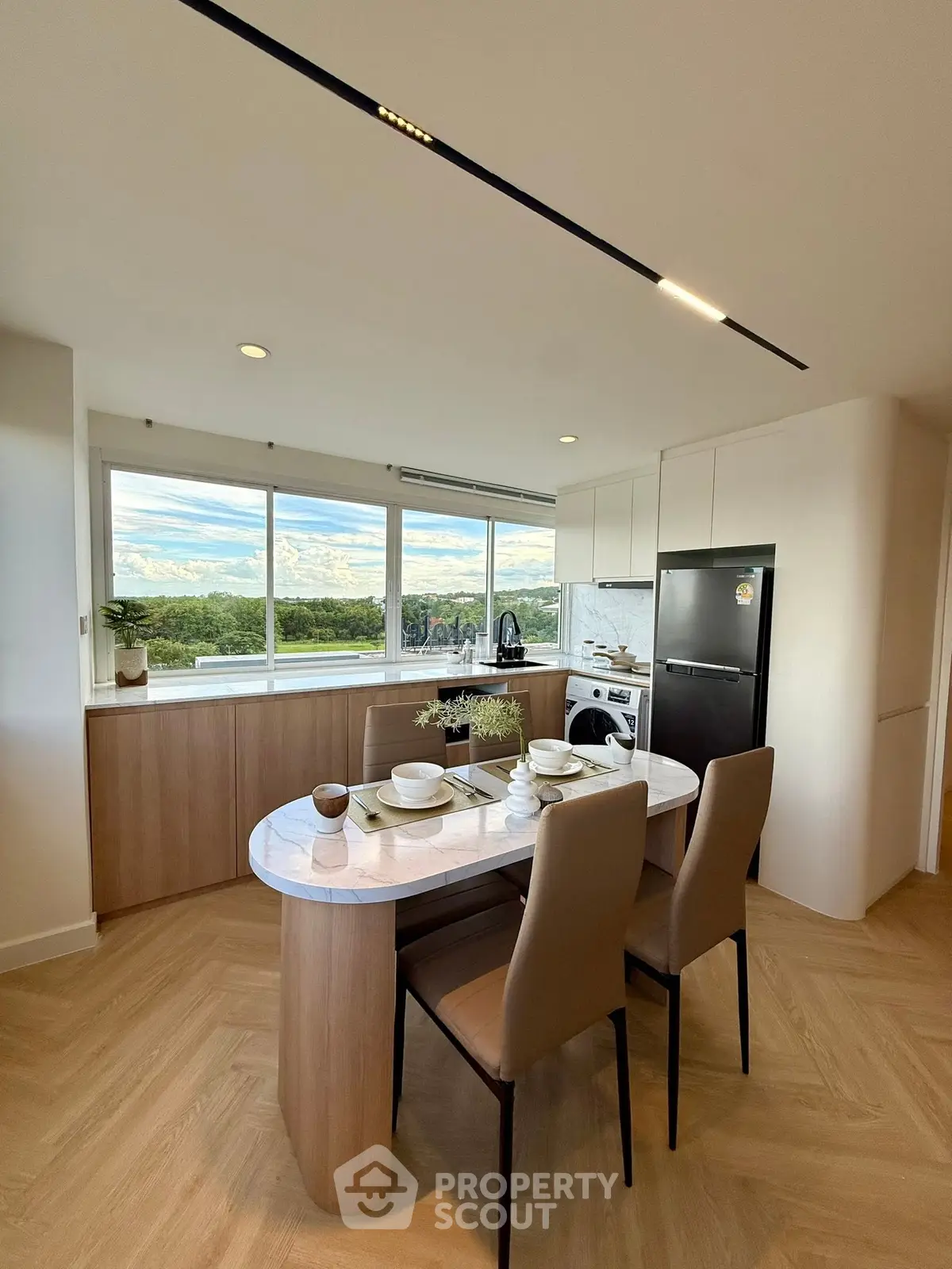 Modern kitchen with open layout and scenic view, featuring sleek appliances and elegant dining area.