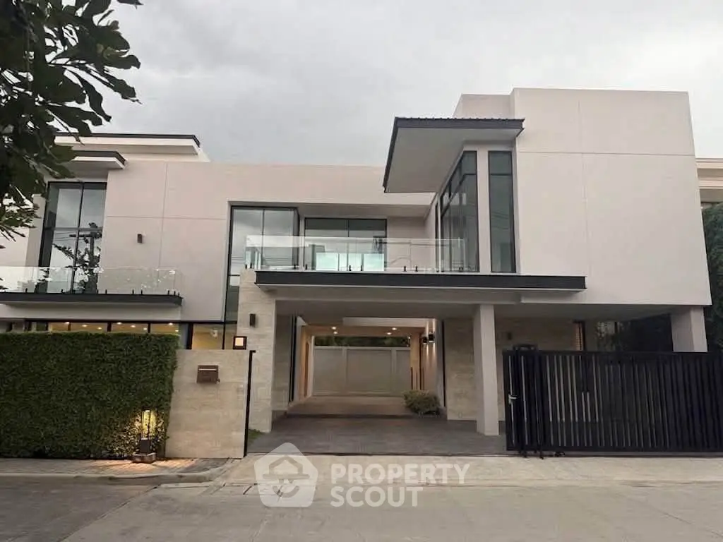 Luxurious modern house with sleek design and spacious driveway, featuring large windows and elegant architecture.
