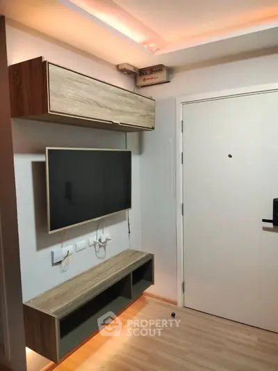 Modern apartment entrance with sleek TV setup and stylish wooden cabinetry.
