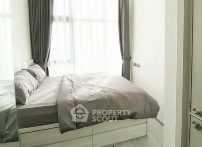 Modern bedroom with elegant curtains and cozy bedding in bright natural light.