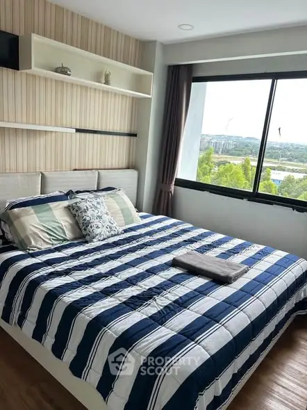 Cozy bedroom with large window offering scenic views, featuring a stylish striped bedspread and modern decor.