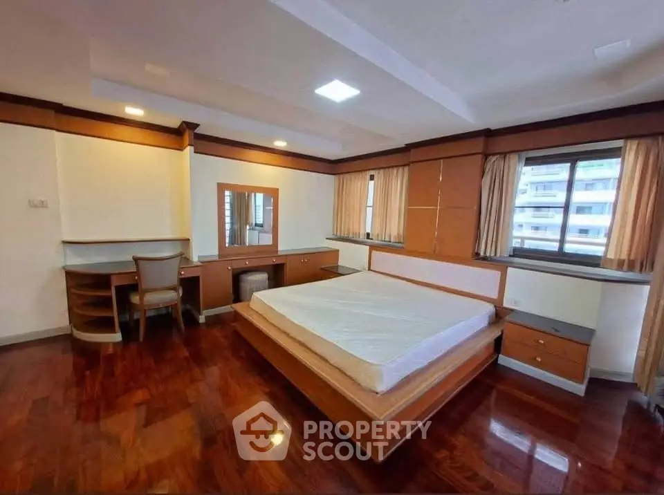 Spacious bedroom with hardwood floors and large windows in modern apartment