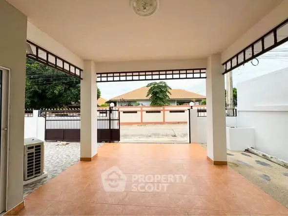 Spacious covered patio with tiled flooring and gated entrance, perfect for outdoor relaxation.