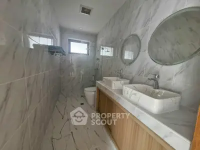 Modern bathroom with dual sinks and marble tiles in a sleek real estate property.
