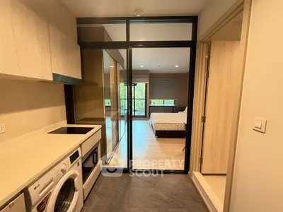 Modern apartment interior with kitchen and bedroom, featuring sleek design and natural light.