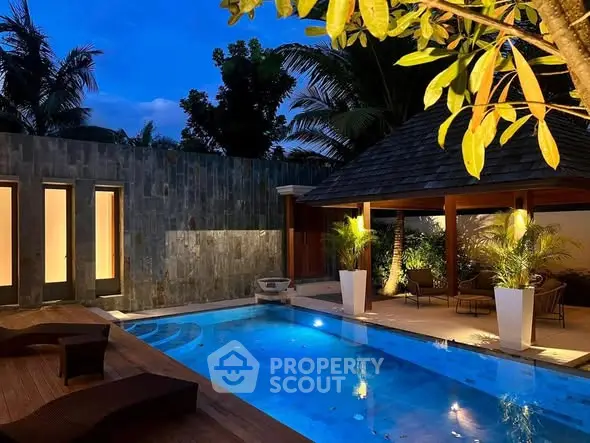 Luxurious outdoor pool area with elegant lighting and lush greenery, perfect for relaxation and entertainment.