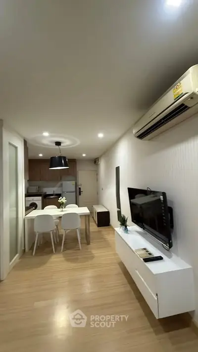 Modern living room with open kitchen, sleek furniture, and air conditioning.