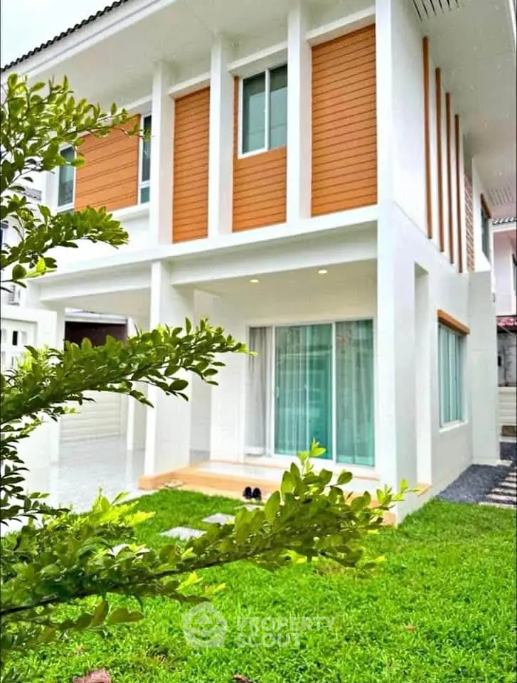 Modern two-story house with lush green lawn and large windows