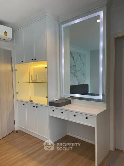 Modern bedroom with built-in storage and illuminated vanity mirror