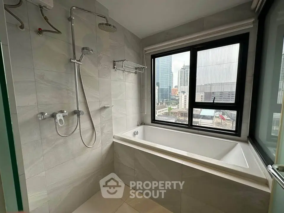 Modern bathroom with city view, featuring a bathtub and shower area.