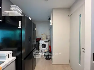 Modern kitchen with sleek black fridge and washing machine in compact layout.