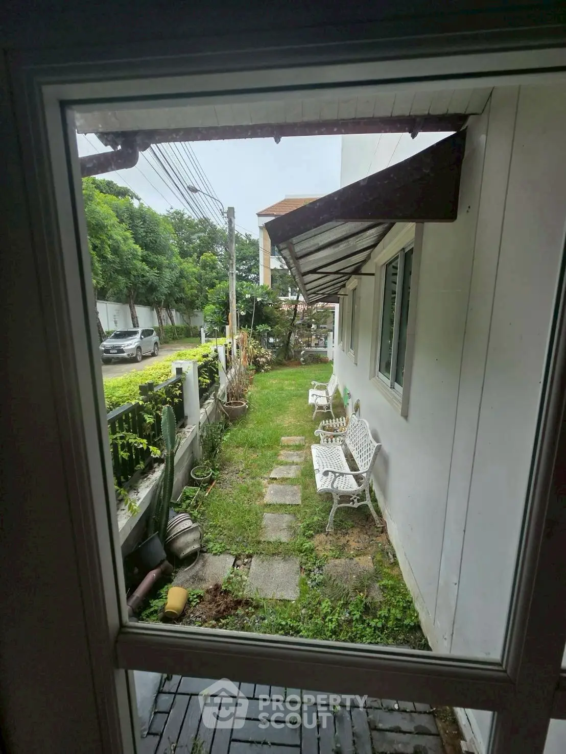Charming garden view from window with outdoor seating and lush greenery