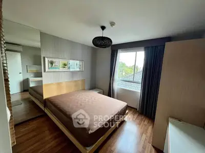 Spacious bedroom with modern decor and large window offering natural light and scenic views.
