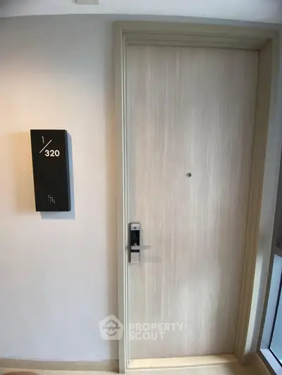 Modern apartment entrance with sleek door and room number 320, featuring a digital lock system.