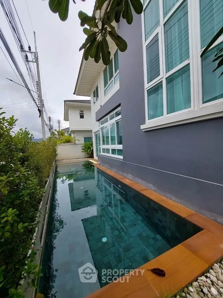 Modern house with sleek pool and large windows in a serene neighborhood.