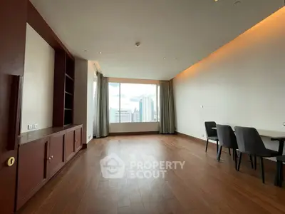 Spacious modern living room with wooden flooring and city view, ideal for urban living.