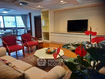 Spacious living room with elegant decor and large TV, featuring a cozy seating area and vibrant plants.