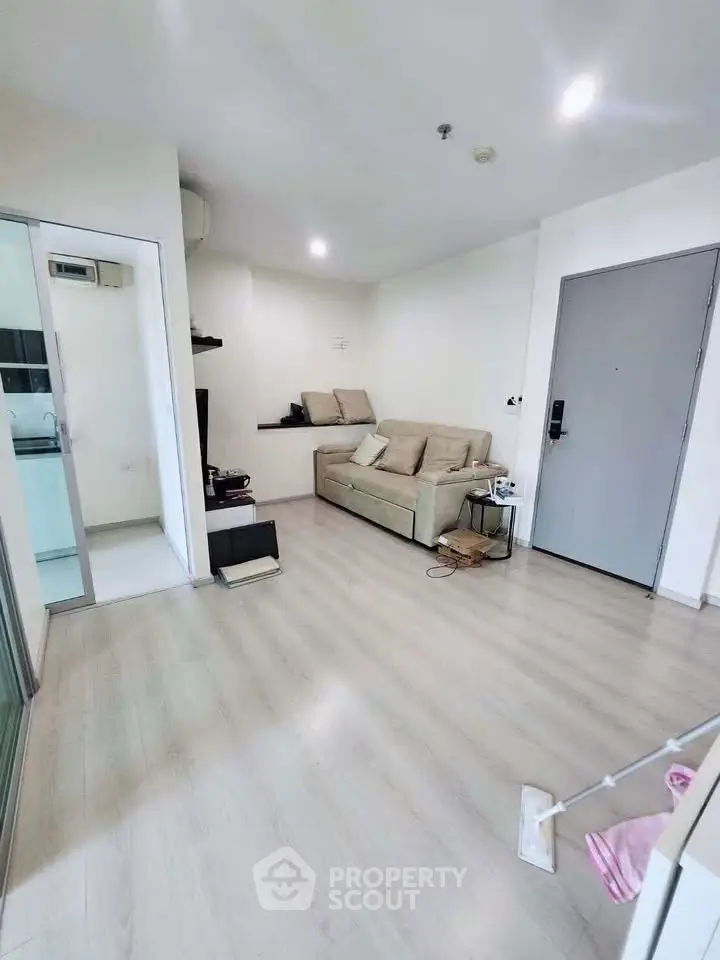 Modern living room with light wood flooring and cozy beige sofa in a bright apartment.