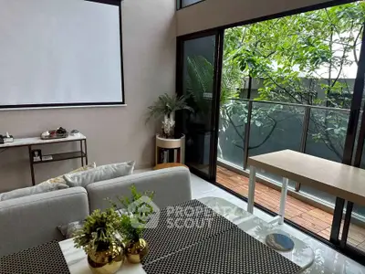 Modern living room with large windows and balcony view, featuring stylish decor and natural light.